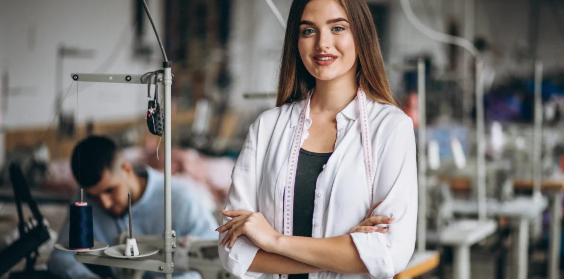 Female tailor working in a uniform manufacturing factory with sewing machines in the background